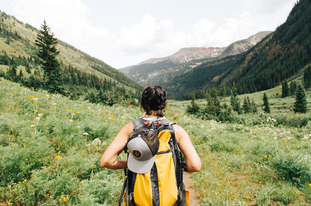 An image showcasing a backpack filled with hiking essentials, including a sturdy pair of hiking boots, a waterproof jacket, a first aid kit, a compass, a water bottle, and a map spread out on a wooden table