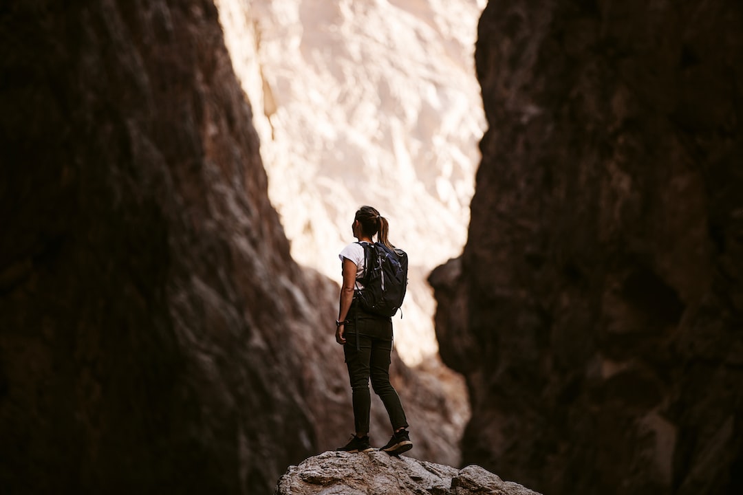 An image showcasing a person hiking on a serene trail, surrounded by lush greenery, towering mountains, and a clear blue sky