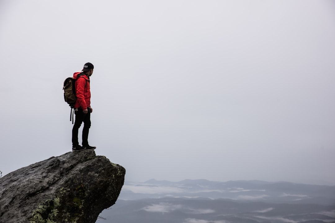 An image showcasing a breathtaking panoramic view from the summit of a rugged mountain, with a winding trail leading into the vibrant wilderness below